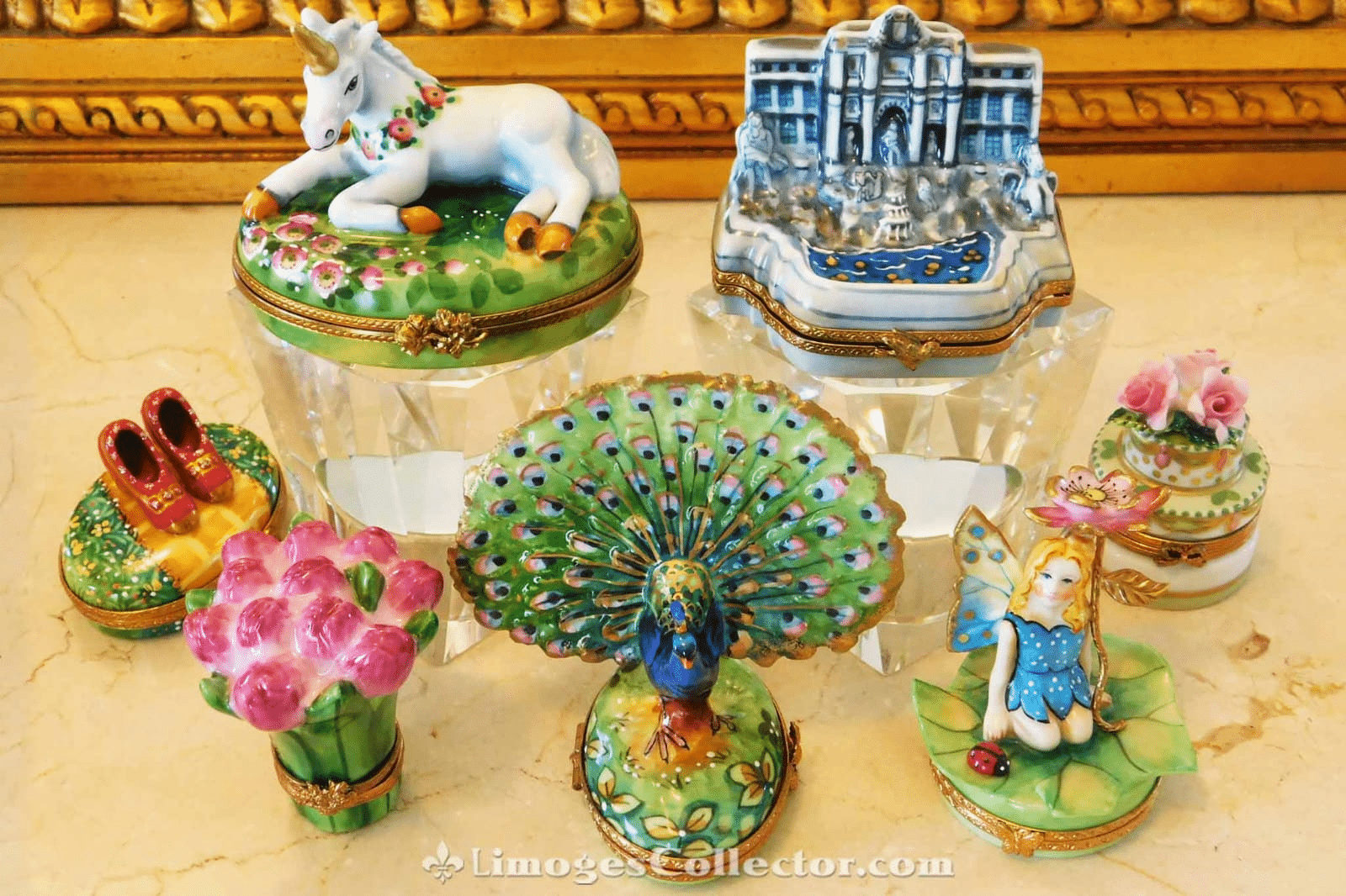 Assorted decorative porcelain trinket boxes featuring unicorn, peacock, and fairy designs on a marble surface