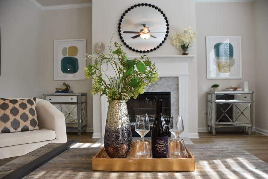 Decorative vase with greenery and wine glasses on tray in modern living room