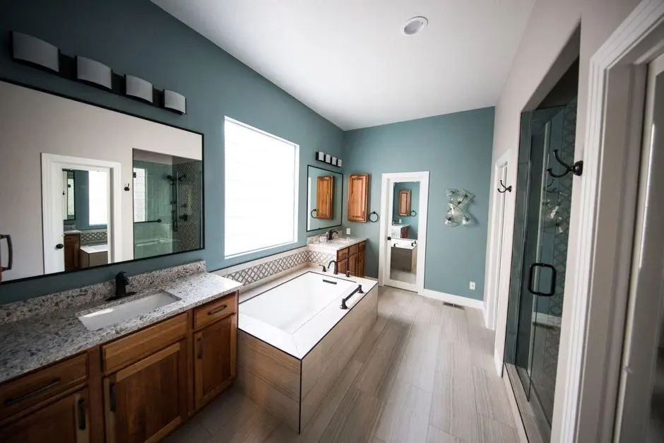 Modern bathroom with freestanding bathtub, granite countertops, and teal accent wall