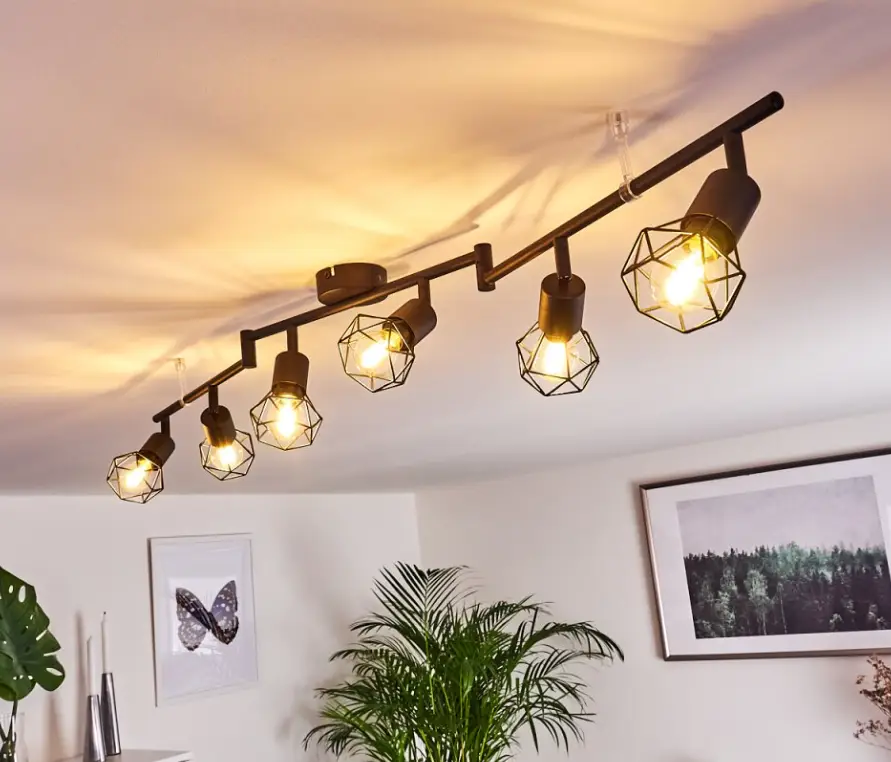 Black geometric pendant lights on ceiling in modern living room with plants and framed art