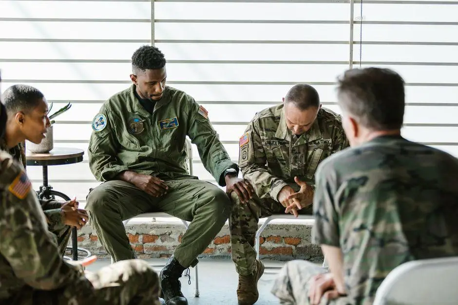 Group of military personnel in discussion, seated in a bright room with large windows